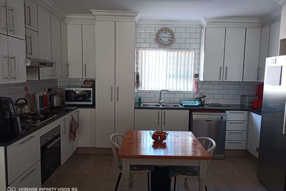 A well-maintained kitchen featuring white cabinetry, subway tile backsplash, granite countertops, and integrated appliances, providing a clean and functional cooking space.
