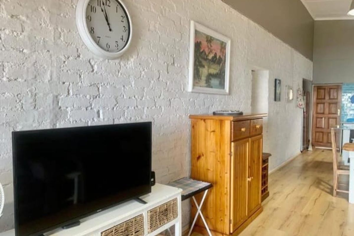 Living area featuring exposed white-painted brick walls, high ceilings, and light-toned timber flooring, creating an open and airy atmosphere.