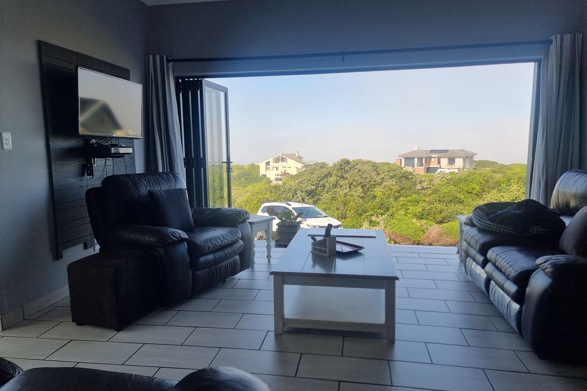Spacious living area featuring large bi-fold doors that open to a scenic outdoor view, complemented by modern tiled flooring.