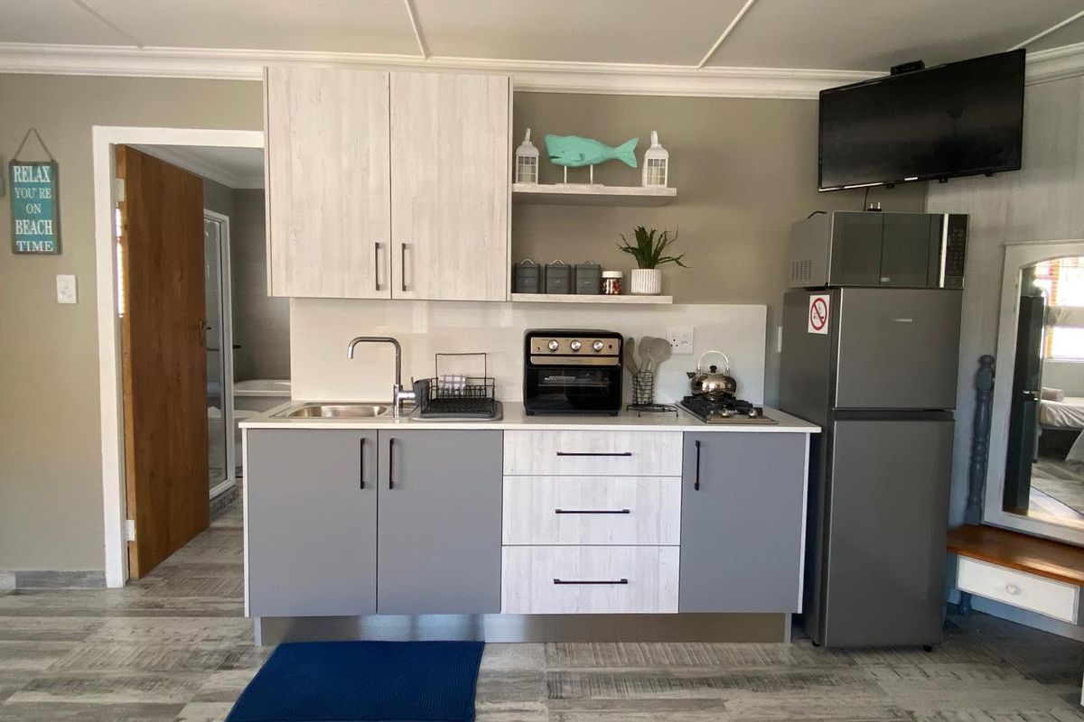 Compact kitchenette featuring modern two-tone cabinetry, integrated sink, and countertop space, providing essential utility in a functional living area.