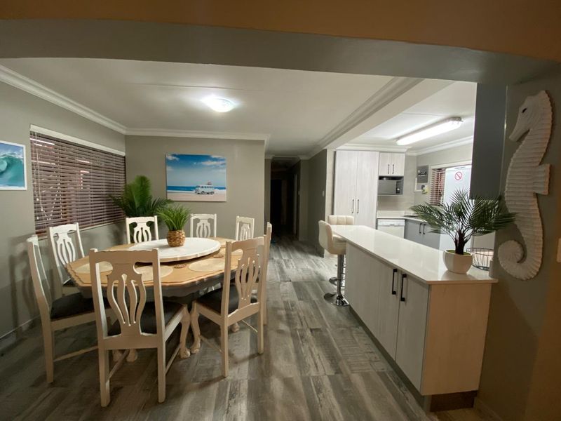 Open plan dining and kitchen area featuring modern cabinetry, a breakfast bar, and wood-look flooring throughout.