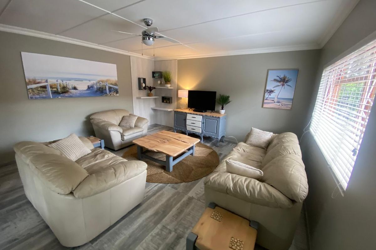 A comfortable living room featuring a ceiling fan, wood-look flooring, and built-in corner shelving, providing a relaxed and functional space.