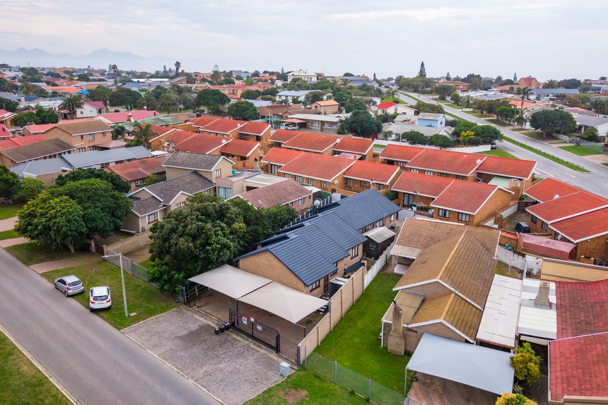 Aerial view of a residential property featuring a dark tiled roof, a paved driveway, and a double carport within a suburban neighbourhood.