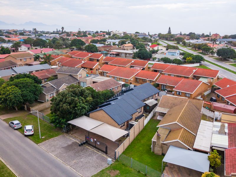 Aerial view of a residential property featuring a dark tiled roof, a paved driveway, and a double carport within a suburban neighbourhood.