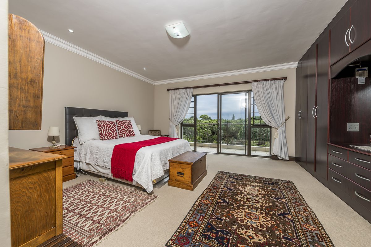 Spacious bedroom featuring built-in dark wood cabinetry, neutral carpeting, and sliding glass doors opening onto a private balcony with scenic views.