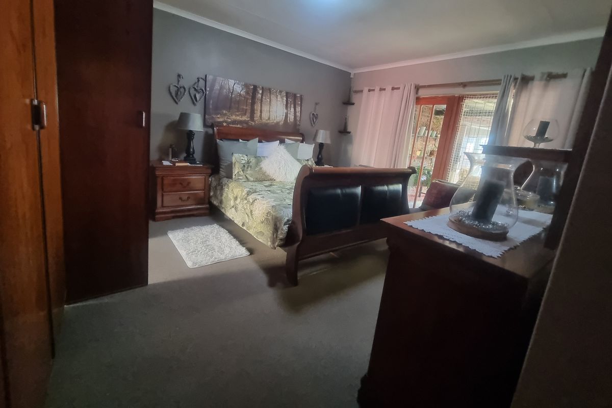 A spacious bedroom featuring built-in wooden cupboards, neutral carpeting, and sliding glass doors that provide direct access to an outdoor patio area.