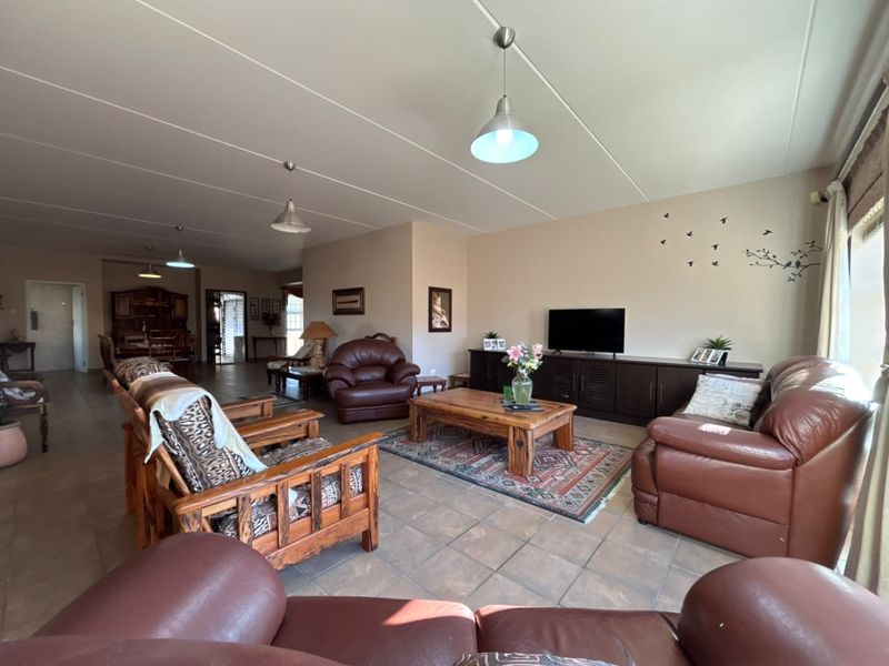Spacious open-plan living area featuring tiled flooring and pendant lighting, offering a versatile layout for lounge and dining arrangements.