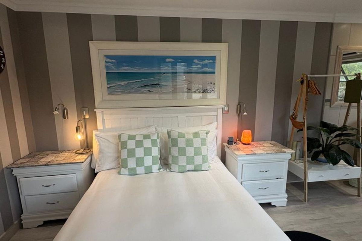 A well-maintained bedroom featuring striped accent wallpaper, recessed downlighting, and coving detail, creating a comfortable and inviting sleeping space.