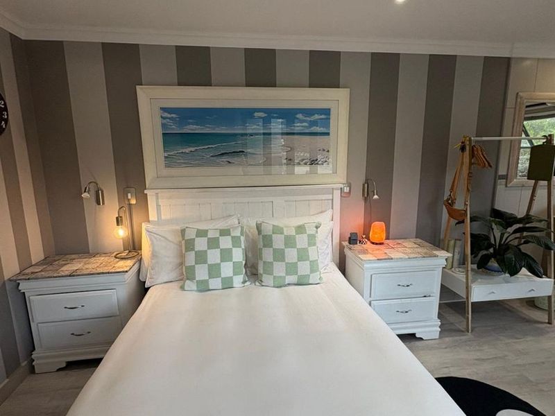 A well-maintained bedroom featuring striped accent wallpaper, recessed downlighting, and coving detail, creating a comfortable and inviting sleeping space.