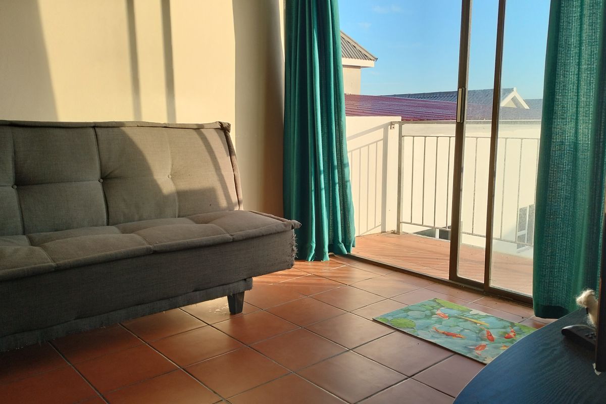 Living room featuring terracotta floor tiles and a sliding glass door providing access to a balcony with metal railing.