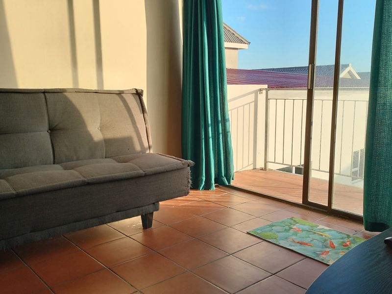 Living room featuring terracotta floor tiles and a sliding glass door providing access to a balcony with metal railing.