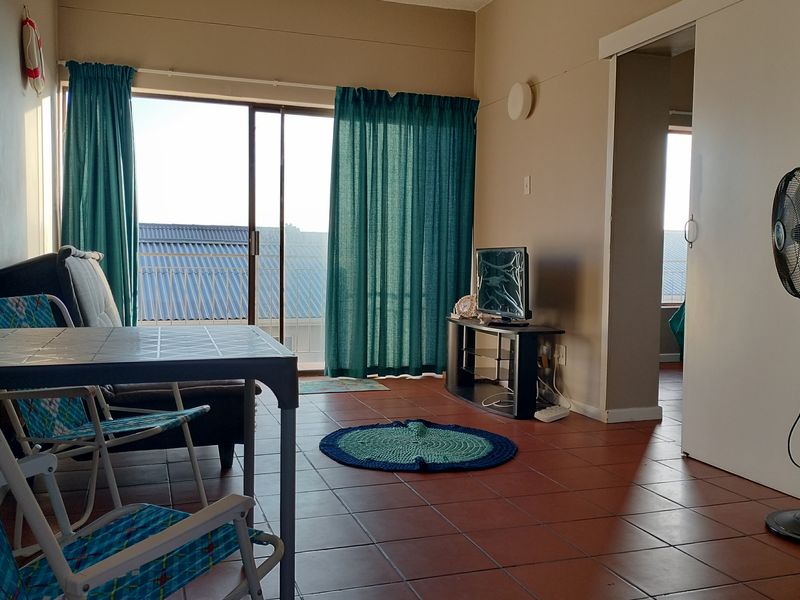 A living area featuring tiled flooring and a large sliding glass door that provides access to an outdoor space.