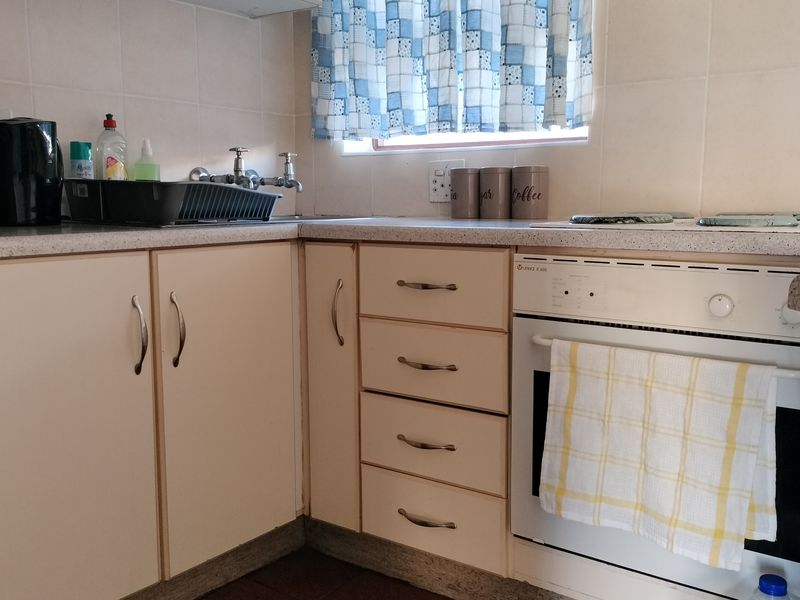 A functional kitchen area featuring built-in cabinetry, laminate countertops, a tiled backsplash, and a built-in oven.