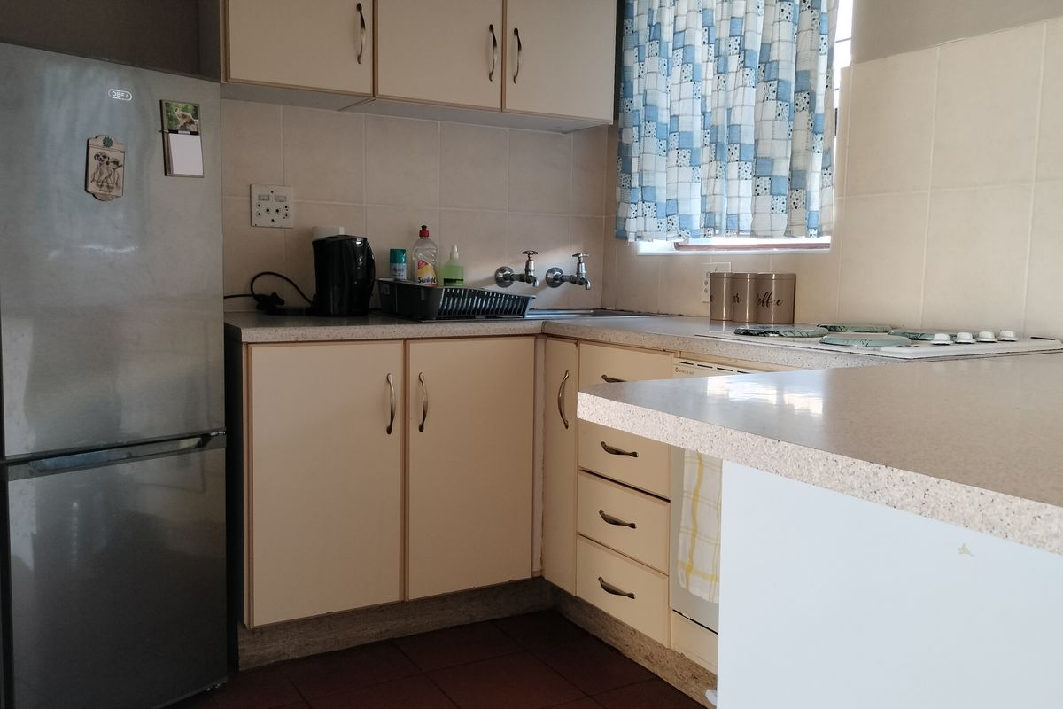 A functional kitchen featuring laminate countertops, built-in cabinetry, and a tiled backsplash, offering a practical layout with potential for modern updates.