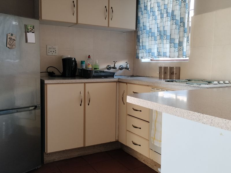 A functional kitchen featuring laminate countertops, built-in cabinetry, and a tiled backsplash, offering a practical layout with potential for modern updates.