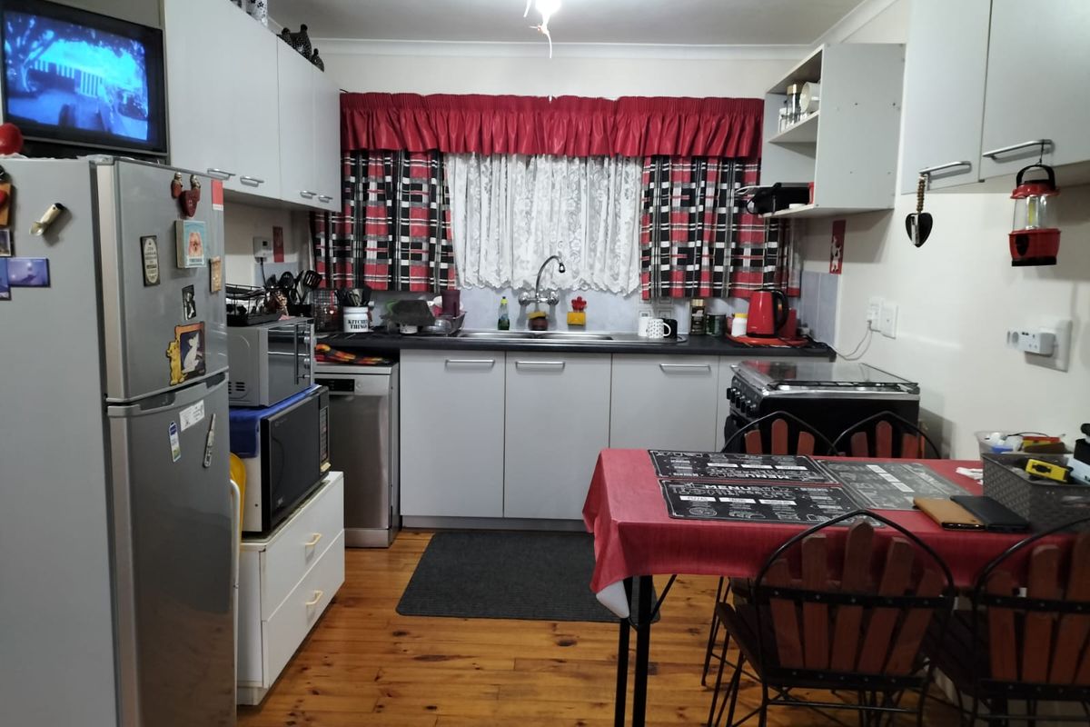 A functional kitchen featuring built-in cabinetry, laminate countertops, a stainless steel sink, and timber flooring, offering potential for a modern update.