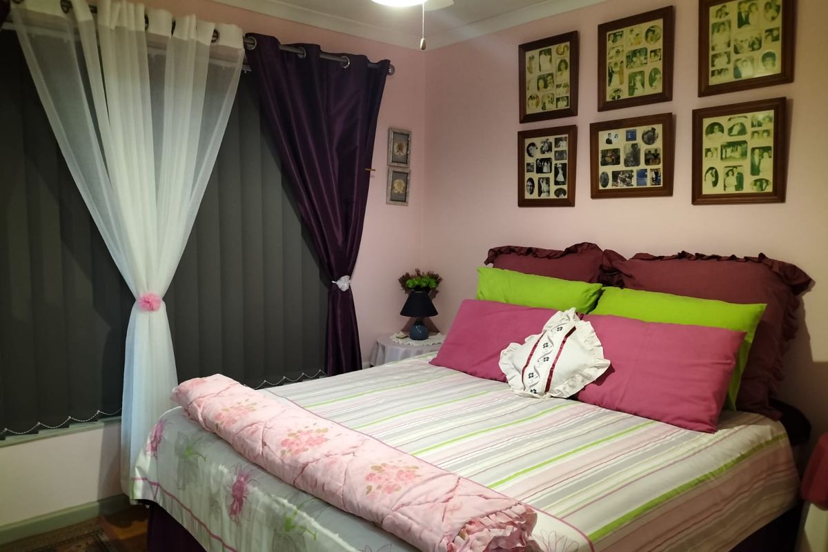 A cozy bedroom featuring a ceiling fan and vertical window blinds, providing a functional and comfortable sleeping space.