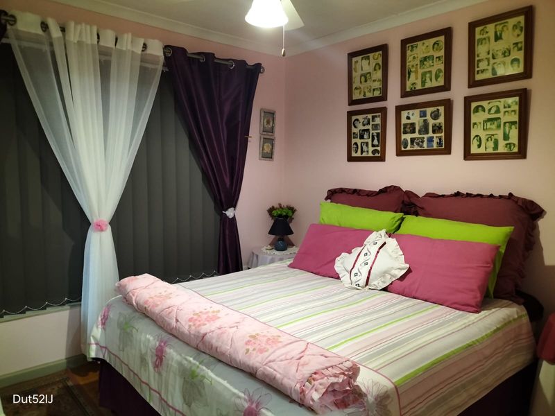 A cozy bedroom featuring a ceiling fan and vertical window blinds, providing a functional and comfortable sleeping space.