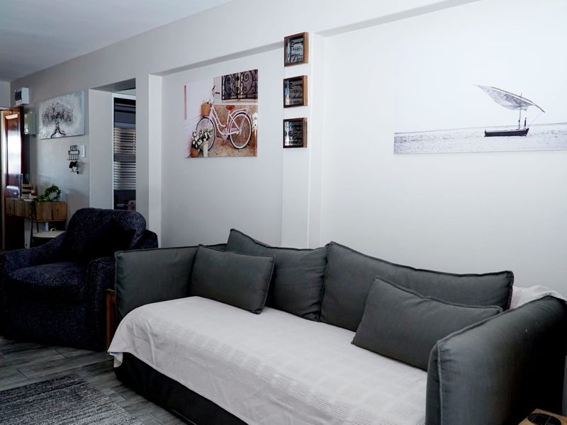 A living room area featuring neutral wall finishes and tiled flooring, providing a functional space for relaxation.