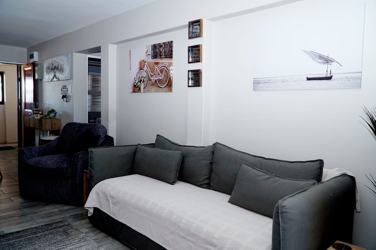 A living room area featuring neutral wall finishes and tiled flooring, providing a functional space for relaxation.