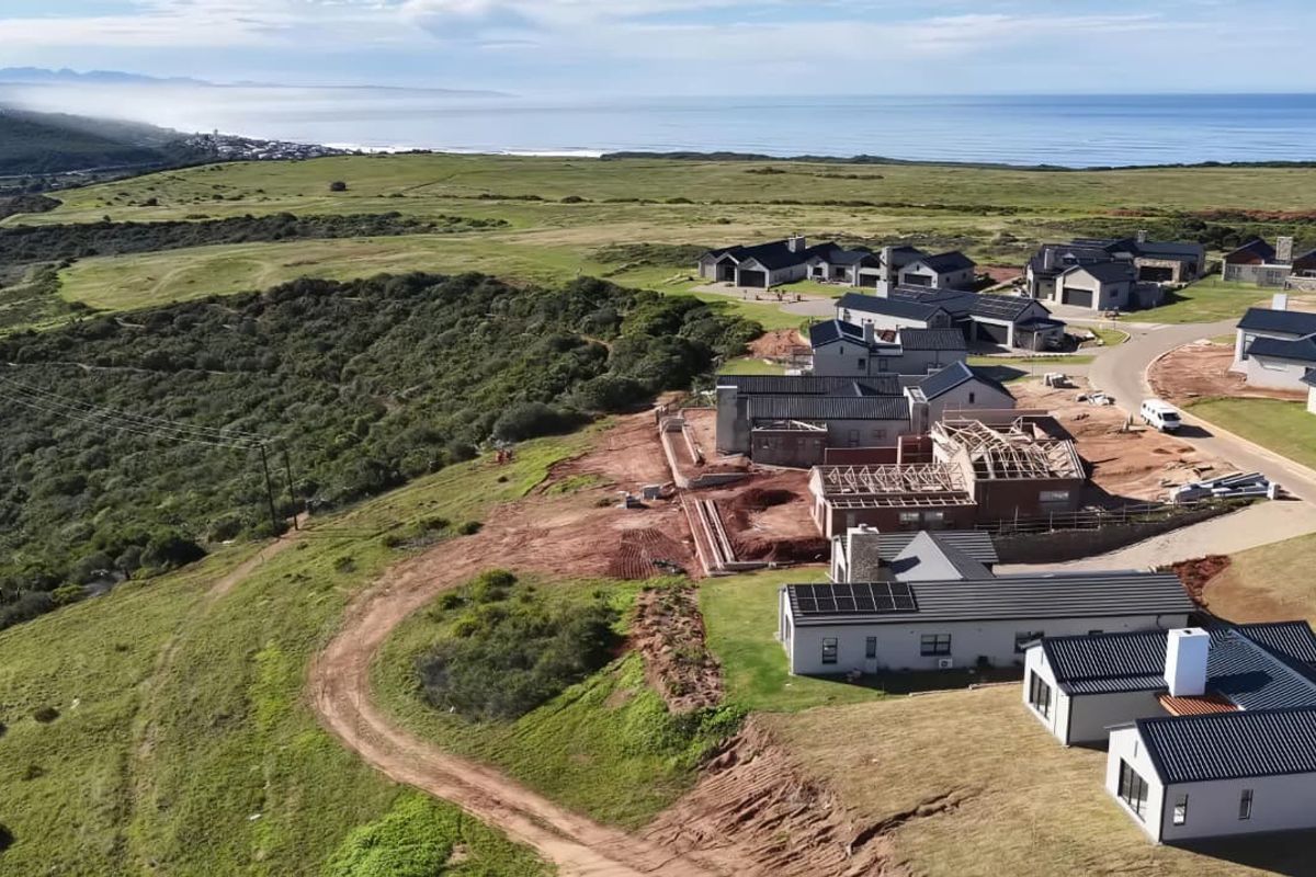 Aerial view of a coastal residential estate showing completed homes and ongoing construction projects with scenic ocean and landscape views.
