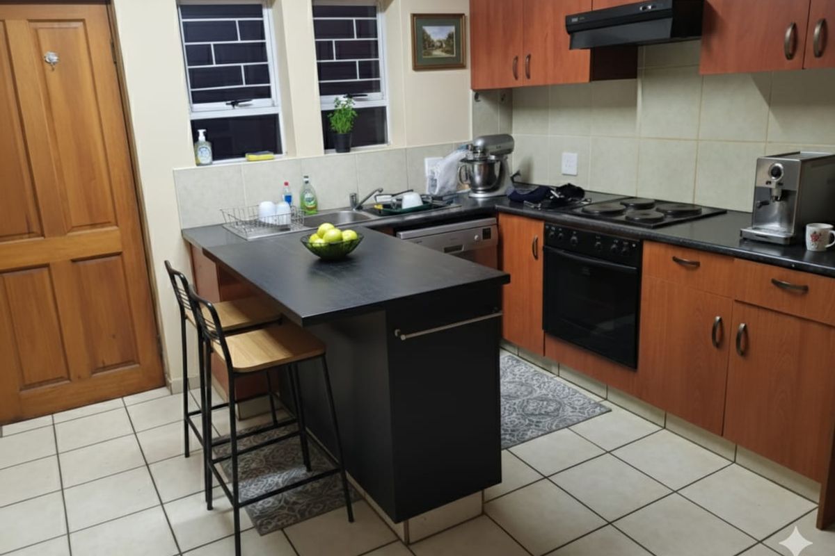 A functional kitchen featuring wood-tone cabinetry, a central island, built-in oven, electric hob, and tiled flooring with practical workspace.
