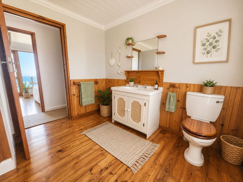 A well-maintained bathroom featuring timber wall paneling, hardwood flooring, a vanity unit with a ceramic basin, and a classic toilet with a wooden seat.