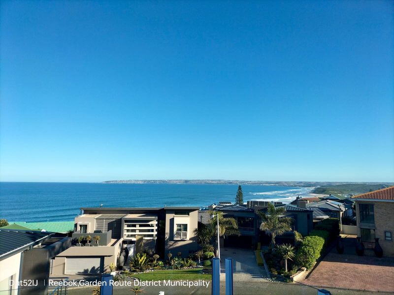 A scenic elevated view overlooking the coastline, ocean, and surrounding residential neighborhood in the Garden Route District.