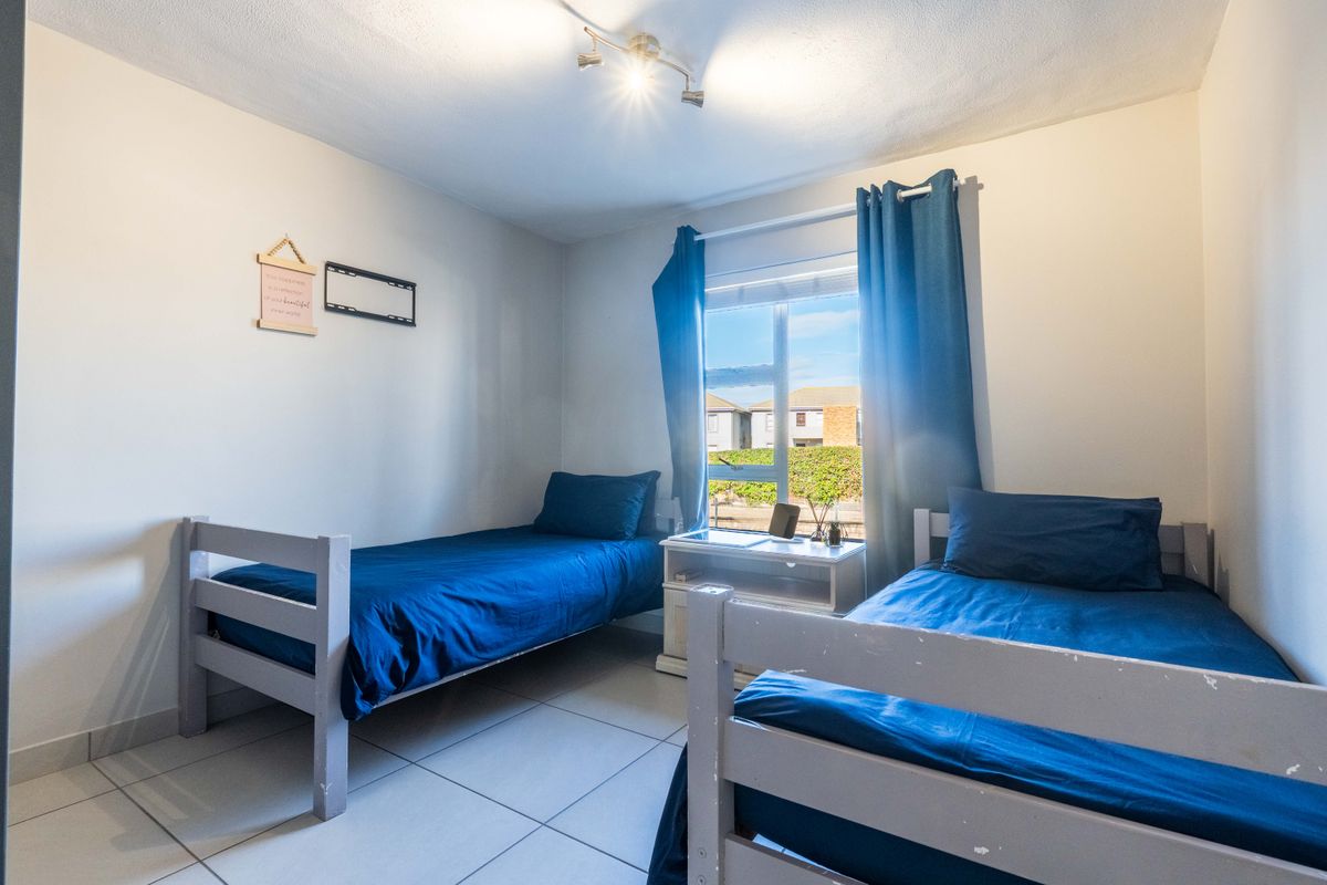 A functional bedroom featuring tiled flooring and a central ceiling spotlight fixture, providing a clean and simple living space.