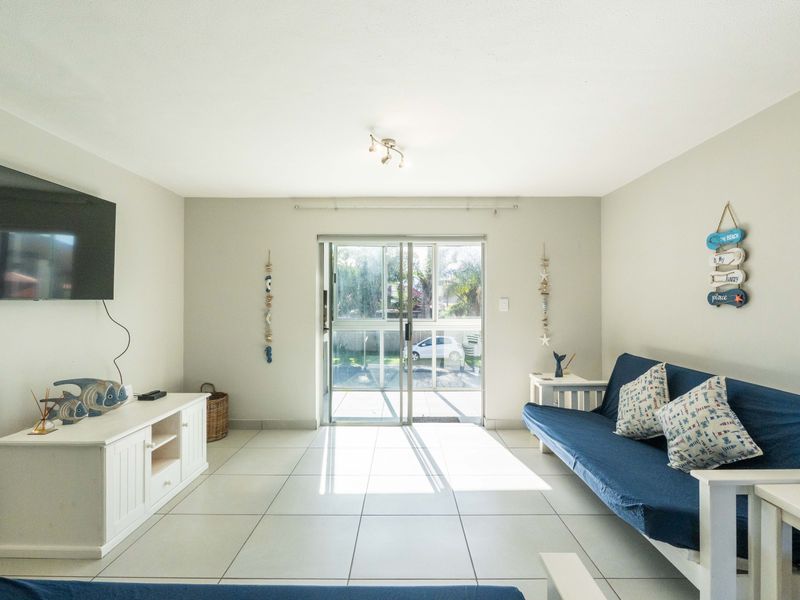 Bright living room featuring neutral tiled flooring and a sliding glass door providing direct access to the exterior.