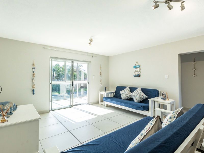 Bright living room featuring neutral tiled flooring and a large sliding glass door providing access to the outdoor area.