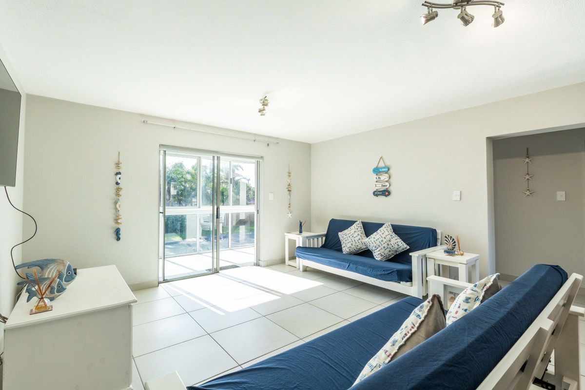 Bright living room featuring neutral tiled flooring and a large sliding glass door providing access to the outdoor area.