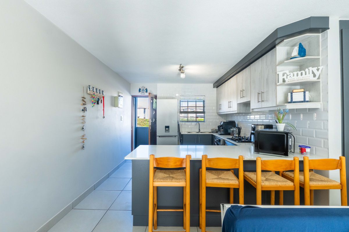 Modern kitchen featuring a breakfast bar, subway tile backsplash, stone countertops, and ample built-in cabinetry with a clean, functional layout.