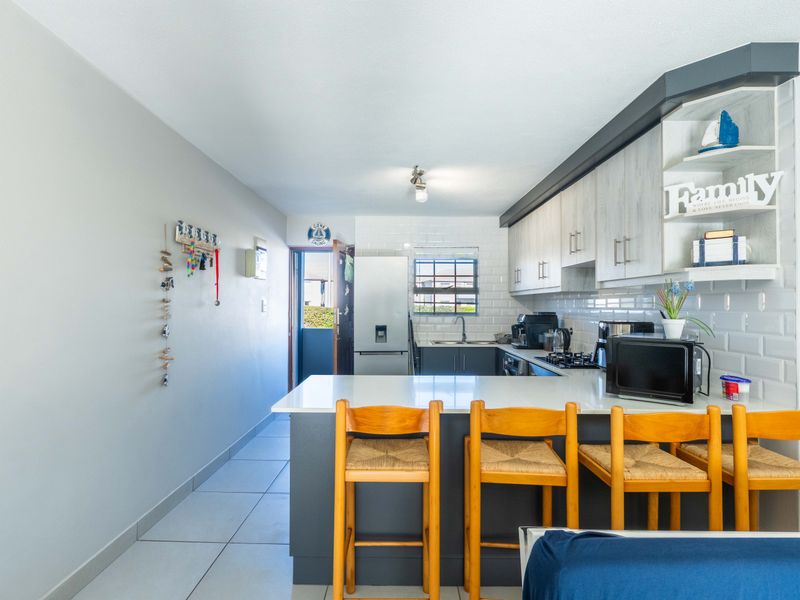 Modern kitchen featuring a breakfast bar, subway tile backsplash, stone countertops, and ample built-in cabinetry with a clean, functional layout.