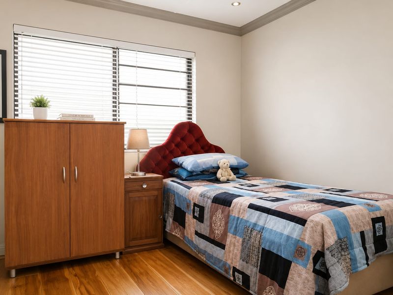 A well-maintained bedroom featuring timber flooring, recessed downlighting, and venetian blinds, offering a clean and neutral living space.