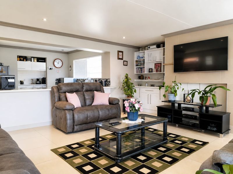 Open plan living area featuring tiled floors, built-in shelving, and a breakfast bar connecting to the kitchen space.