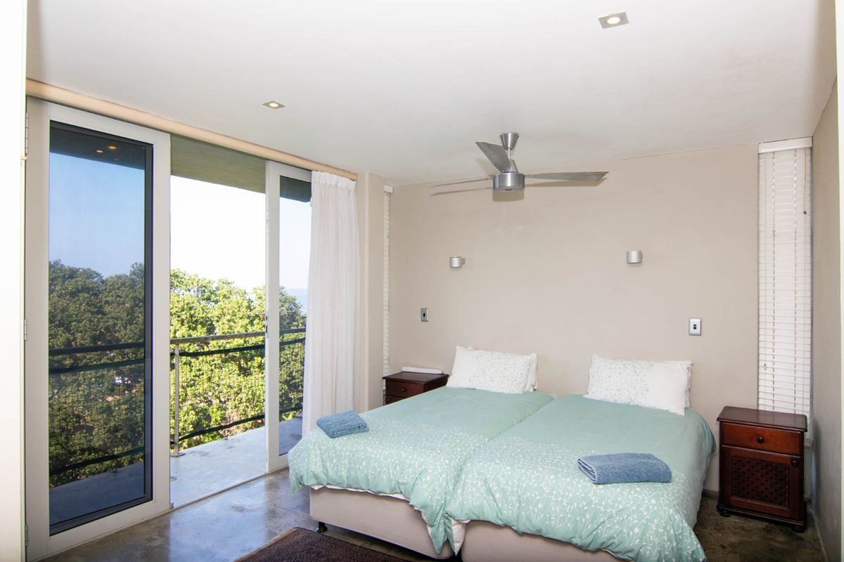 A bedroom featuring a ceiling fan, recessed lighting, and sliding glass doors that open onto a private balcony with scenic views.