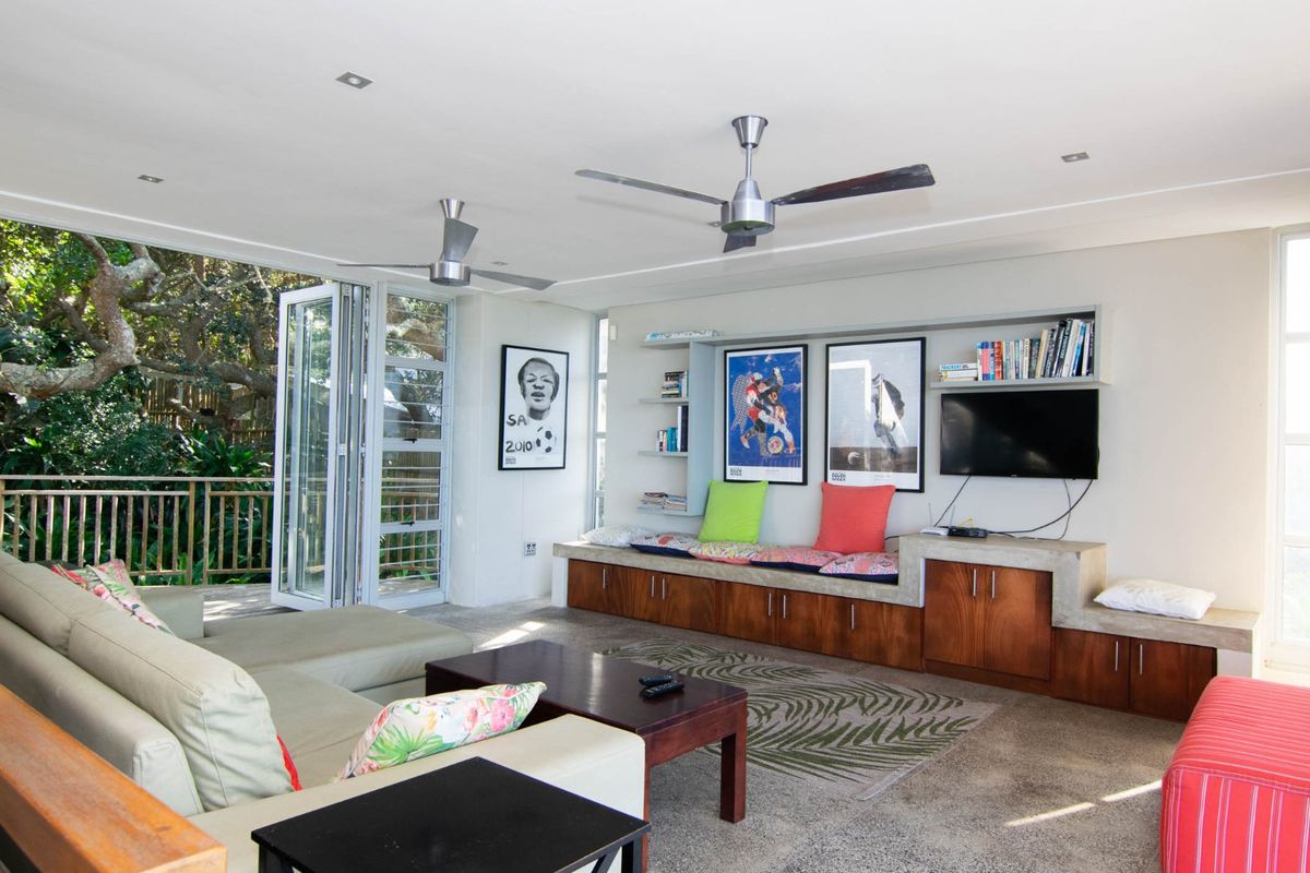 Spacious living area featuring built-in cabinetry, concrete bench seating, ceiling fans, and large bi-fold doors opening onto an outdoor deck.