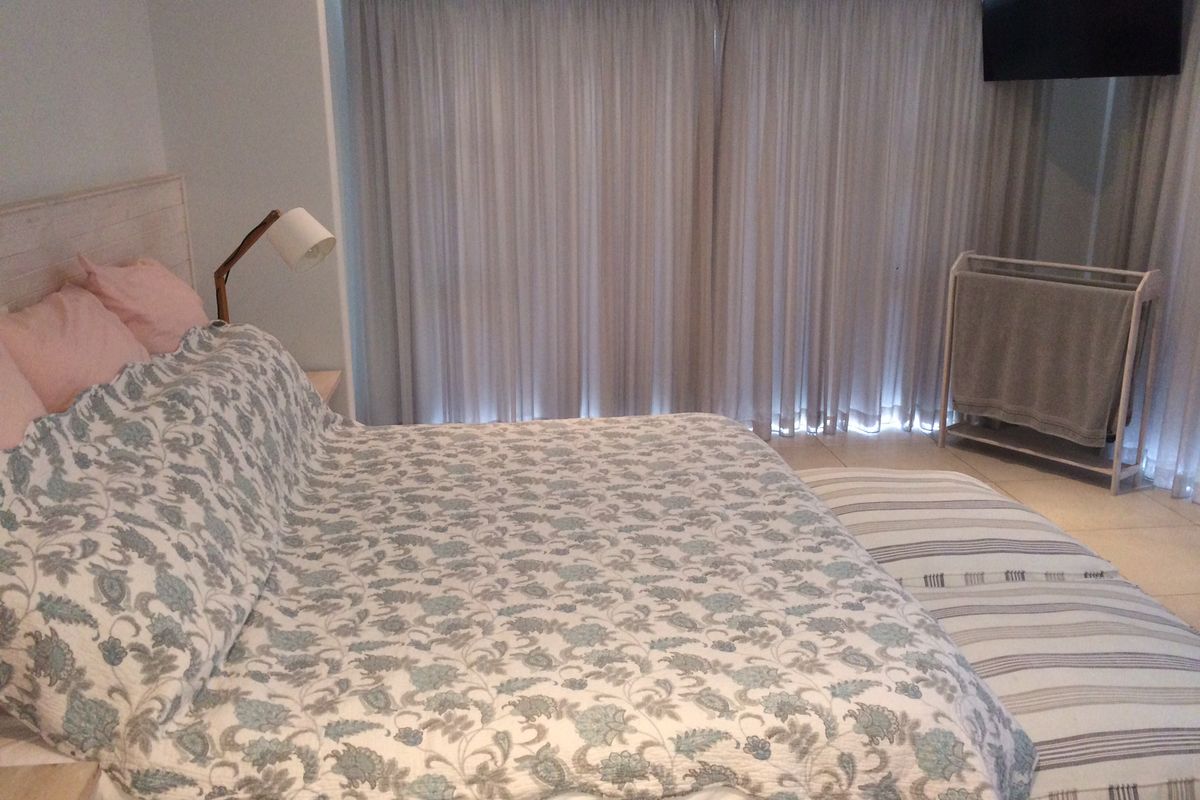 A bedroom featuring tiled flooring, built-in bedside shelving, and floor-to-ceiling curtains covering a large window.