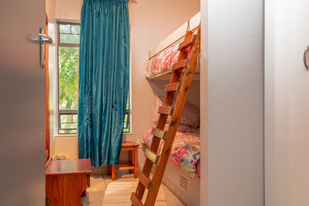 A compact bedroom featuring tiled flooring, a window with natural light, and built-in space for a bunk bed configuration.