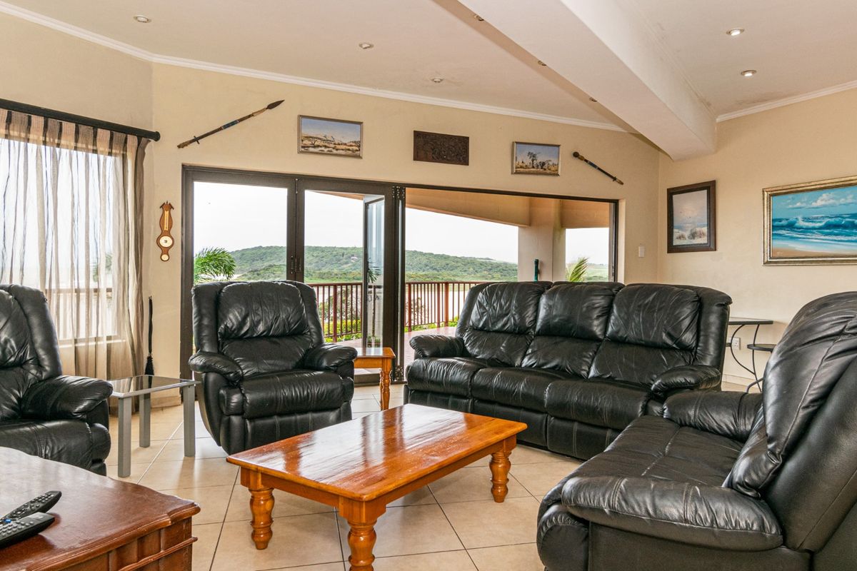 Spacious living room featuring tiled flooring, recessed lighting, and large sliding glass doors that open onto a scenic outdoor balcony area.
