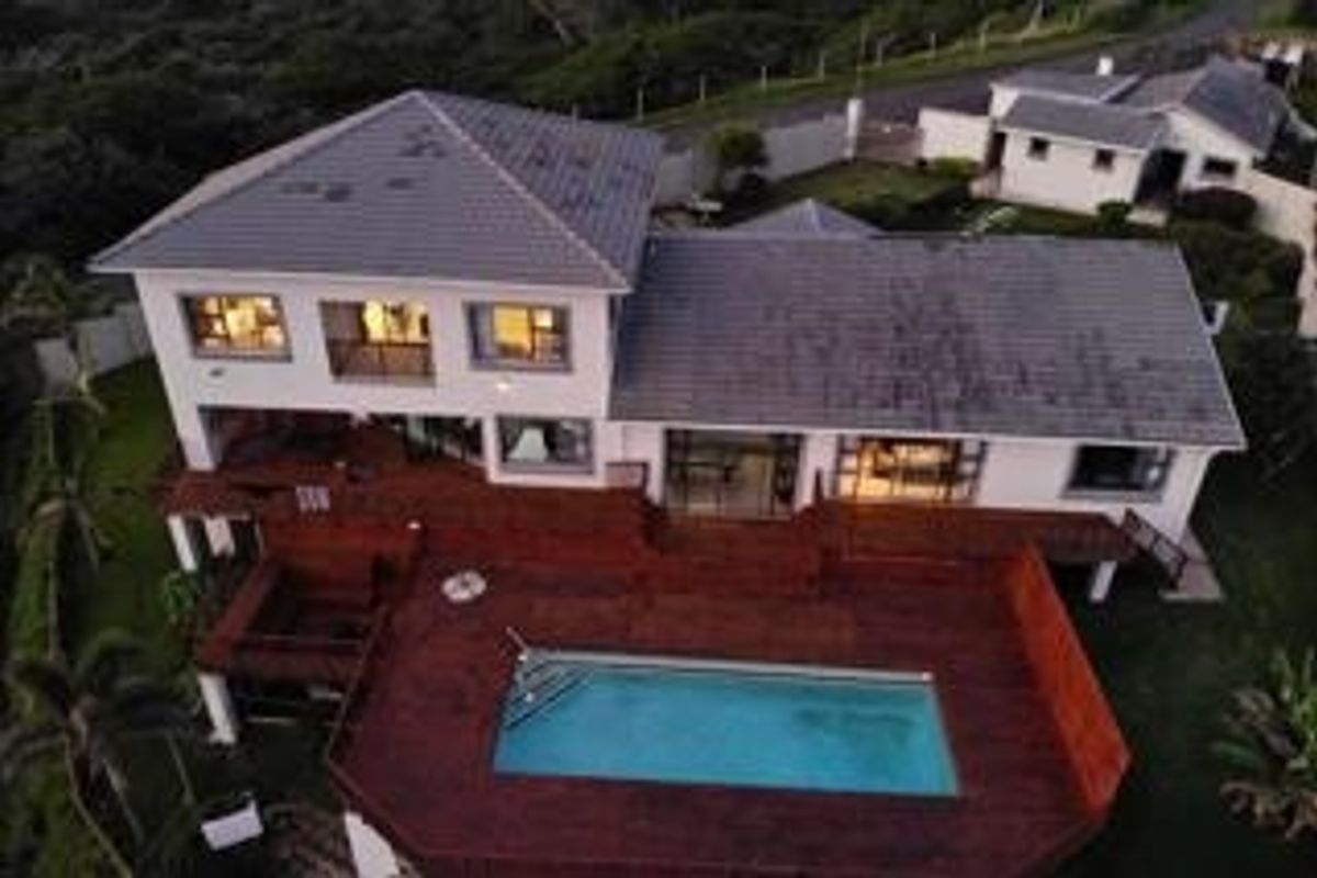 Aerial view of a two-story residential property featuring a swimming pool, extensive timber decking, and a tiled roof.