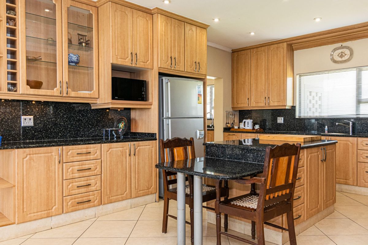A functional kitchen featuring wooden cabinetry, granite countertops, and a central island with integrated seating, offering ample storage and workspace.