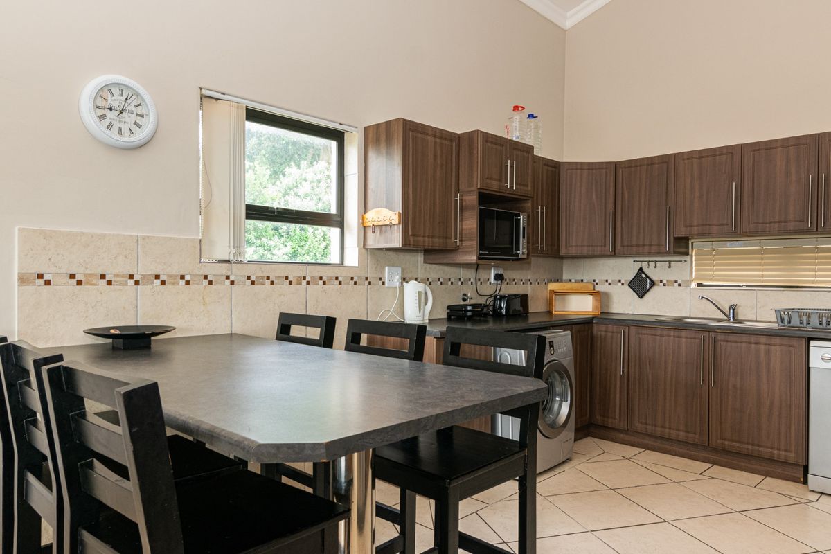 A functional kitchen featuring dark wood cabinetry, tiled backsplash, integrated dishwasher, and a built-in microwave, with an adjacent dining area.