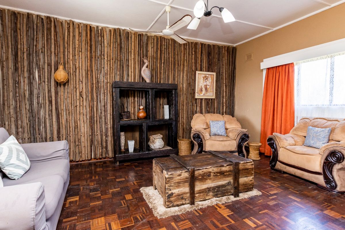 A living room featuring a rustic timber-clad feature wall, parquet flooring, and a ceiling fan, offering a warm and traditional aesthetic.