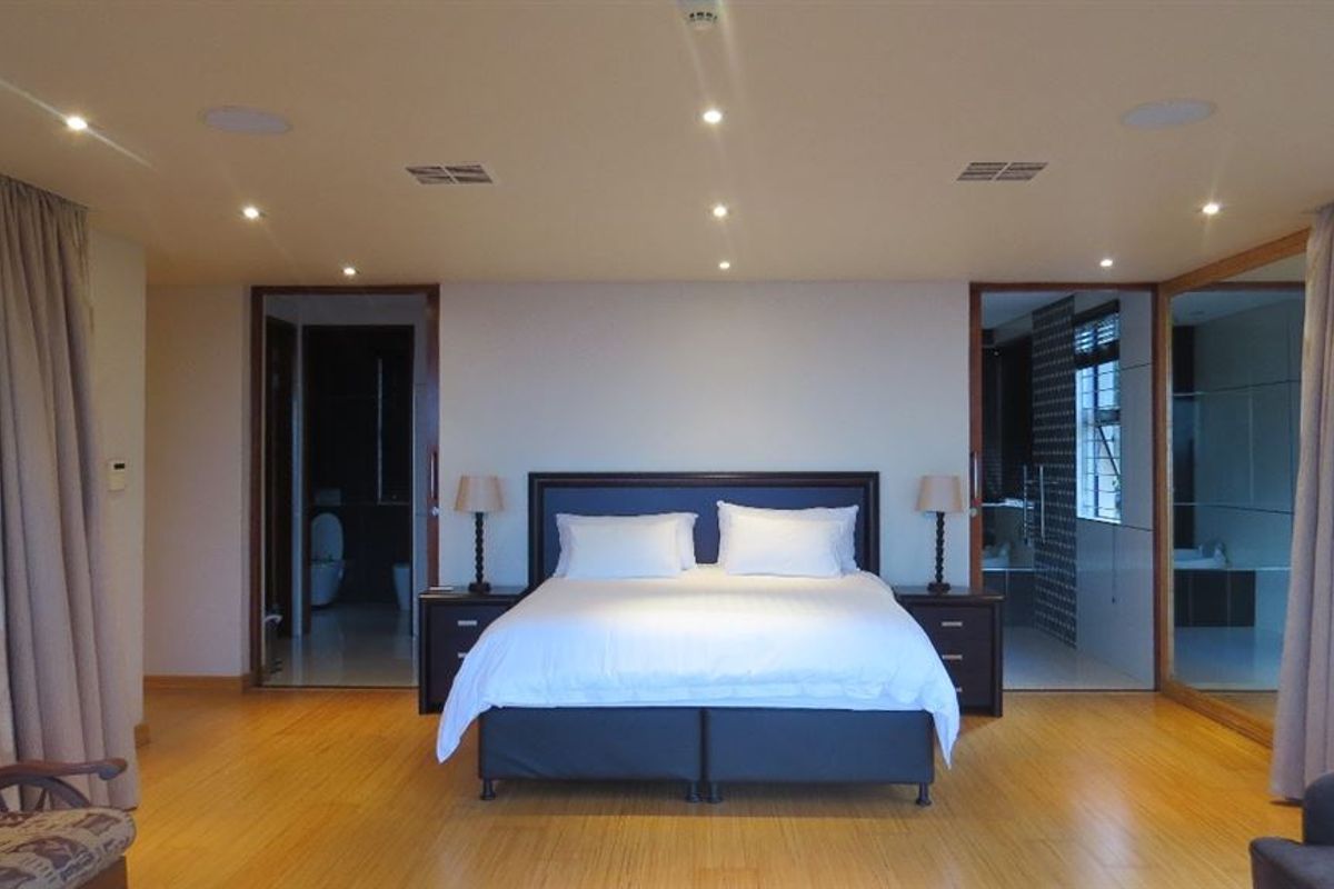 Spacious bedroom featuring bamboo flooring, recessed downlighting, integrated ceiling speakers, and direct access to an en-suite bathroom.