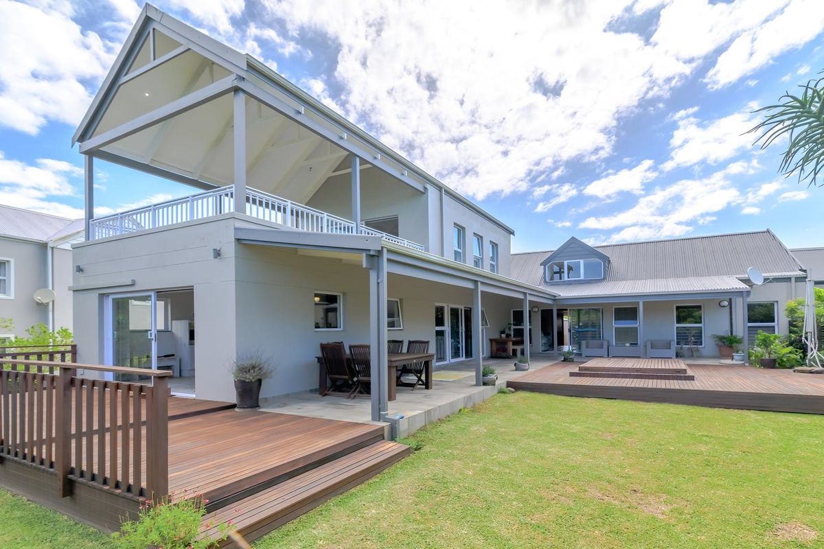 Spacious rear exterior featuring a large timber deck, covered patio area, and a well-maintained lawn, ideal for outdoor entertaining and relaxation.