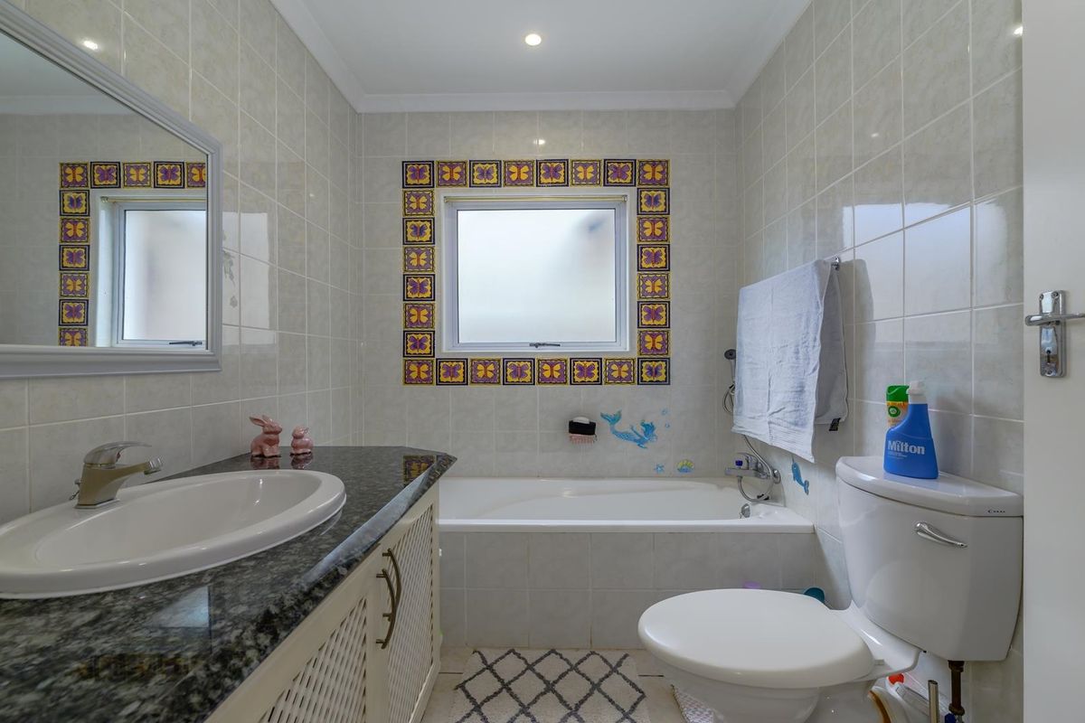 A functional bathroom featuring a built-in bathtub, vanity with granite countertop, integrated sink, and tiled wall finishes.