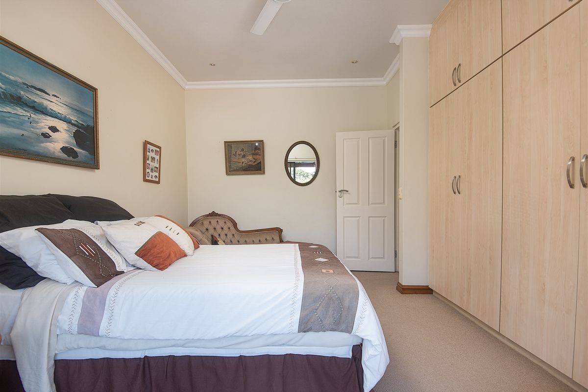 A well-maintained bedroom featuring neutral walls, carpeted flooring, and extensive floor-to-ceiling built-in wooden cabinetry.