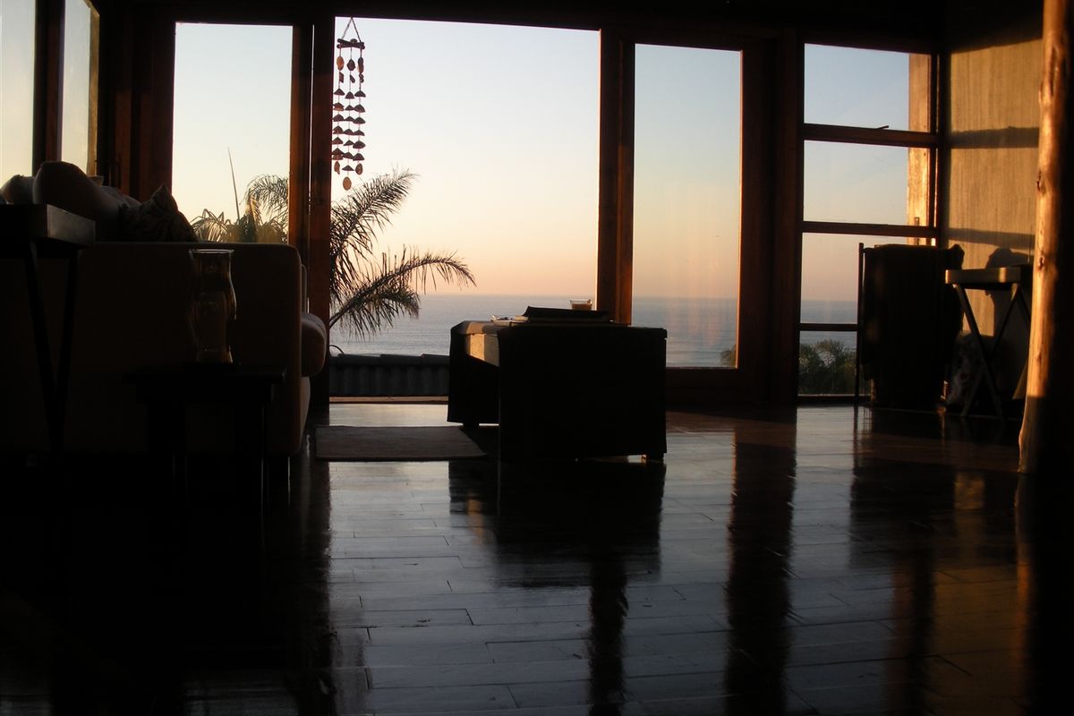 A living room featuring expansive floor-to-ceiling timber-framed windows that offer panoramic ocean views and abundant natural light.